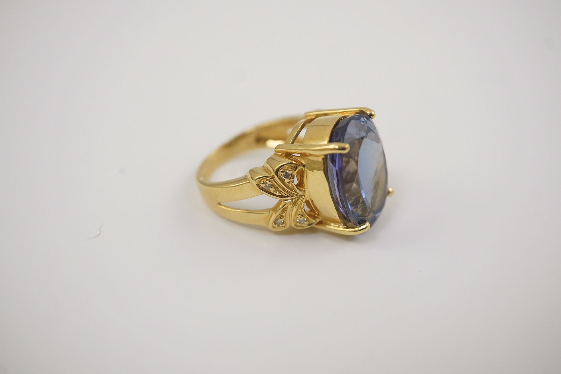 A modern 18ct gold and single stone oval cut tanzanite set dress ring, with eight stone diamond chip set shoulders